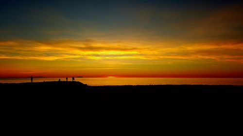 Scenic view of beach against dramatic sky during sunset