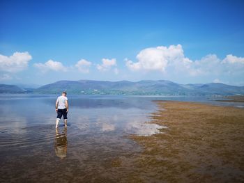 Man standing at beach against sky