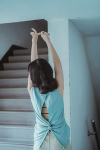 Rear view of woman standing against staircase