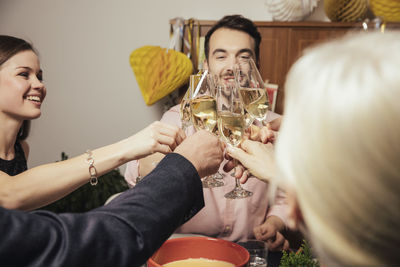 Laughing friends clinking glasses with champagne at new year's eve