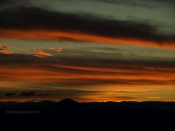 Scenic view of dramatic sky over silhouette landscape