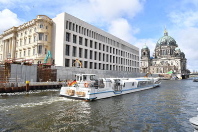 Boats in canal by buildings against sky in city