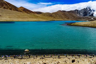 Scenic view of turquoise lake by mountain range