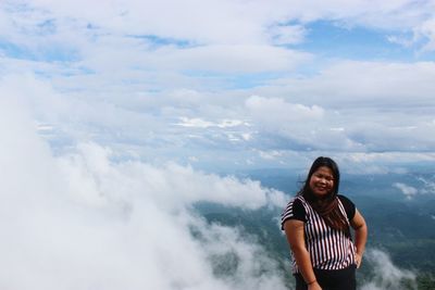 Portrait of young woman standing against sky