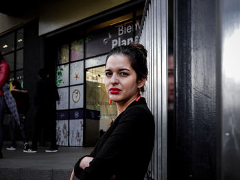 Side view portrait of young woman with arms crossed standing in city