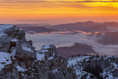 Scenic view of snowcapped mountains against orange sky