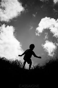 Silhouette boy standing on field against sky