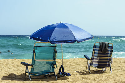 Deck chairs at beach against clear sky