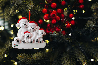 Christmas toy figurines of polar bears in a santa claus hat hanging on the christmas tree branches.