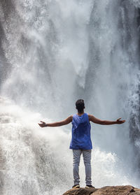 Rear view of man standing against waterfall