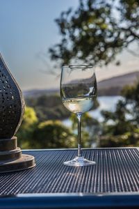 Close-up of wineglass on table against sky