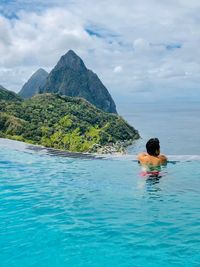 Rear view of man in swimming pool against sea