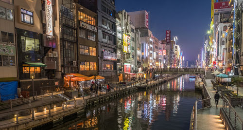 Canal amidst illuminated buildings in city at night