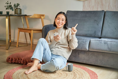 Portrait of young woman sitting on sofa at home