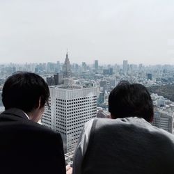 Rear view of men standing against cityscape