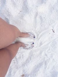 Low section of woman standing on sand