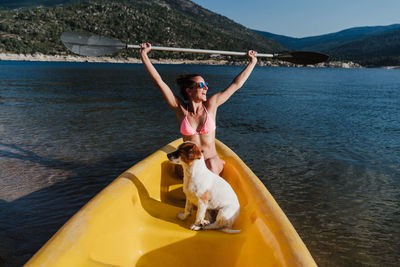 Smiling woman canoeing with dog in lake