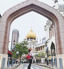 Woman by buildings in city against sky