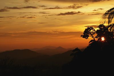 Scenic view of silhouette mountains against orange sky