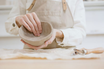 Midsection of man making clay on table