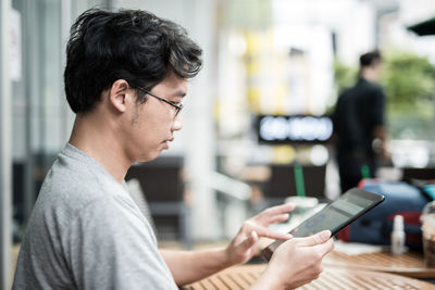 Man using digital tablet while sitting on table at cafe