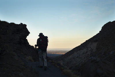 People standing on rock against sky during sunset