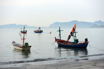 Fishing boats moored in sea against clear sky