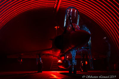 Man standing by illuminated airplane at night