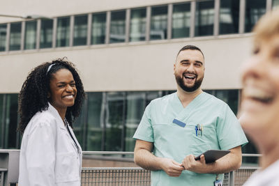 Cheerful male and female healthcare workers standing outside hospital