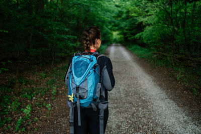 Rear view of man walking on road in forest