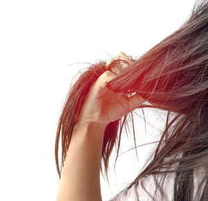 Cropped image of woman with hand tangled hair against white background