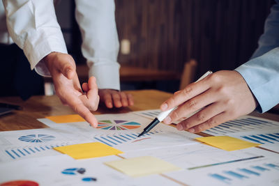 Cropped hands of businessmen analyzing paperwork on table