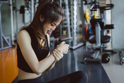 Young woman suffering from joint pain while exercising in gym