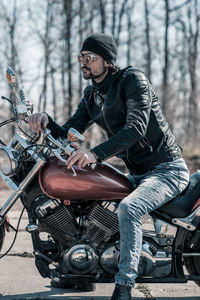 Mid adult man sitting on motorcycle in forest