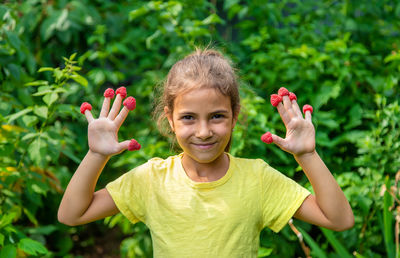 Portrait of smiling girl with raspberry on finger tips