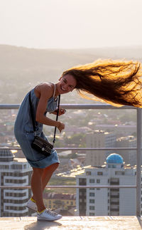 Full length of woman standing by cityscape against sky