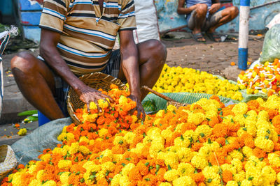 Midsection of person holding flowers in market