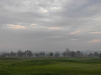 Scenic view of grassy field against cloudy sky