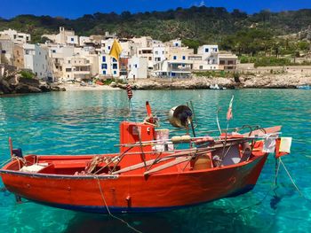 Boat moored in sea against buildings