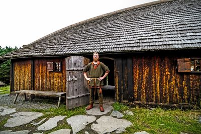 Full length of man standing against wooden house