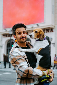 Portrait of man with dog standing outdoors