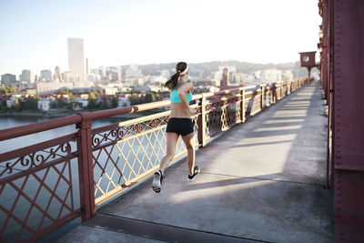 Rear view of determined sporty woman running on bridge