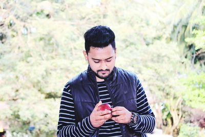 Young man with apple standing on field