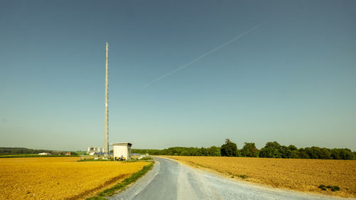 Road amidst field against clear sky