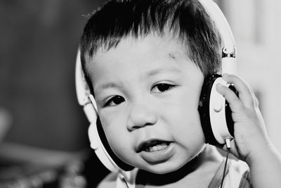 Close-up portrait of cute baby boy listening to music from headphones