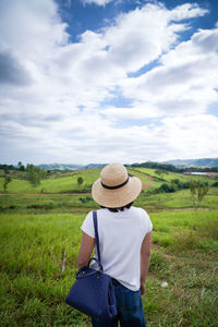 Rear view of man standing on field against sky