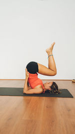 Side view of woman exercising against white background