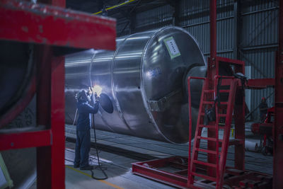 Man welding large steel tank in factory