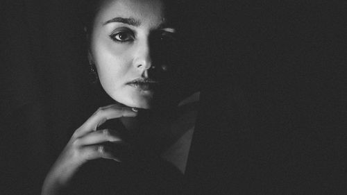 Close-up portrait of young woman against black background