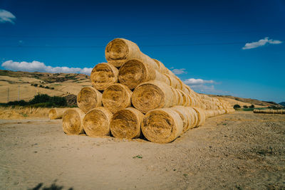 Stack of hay bales on field against sky